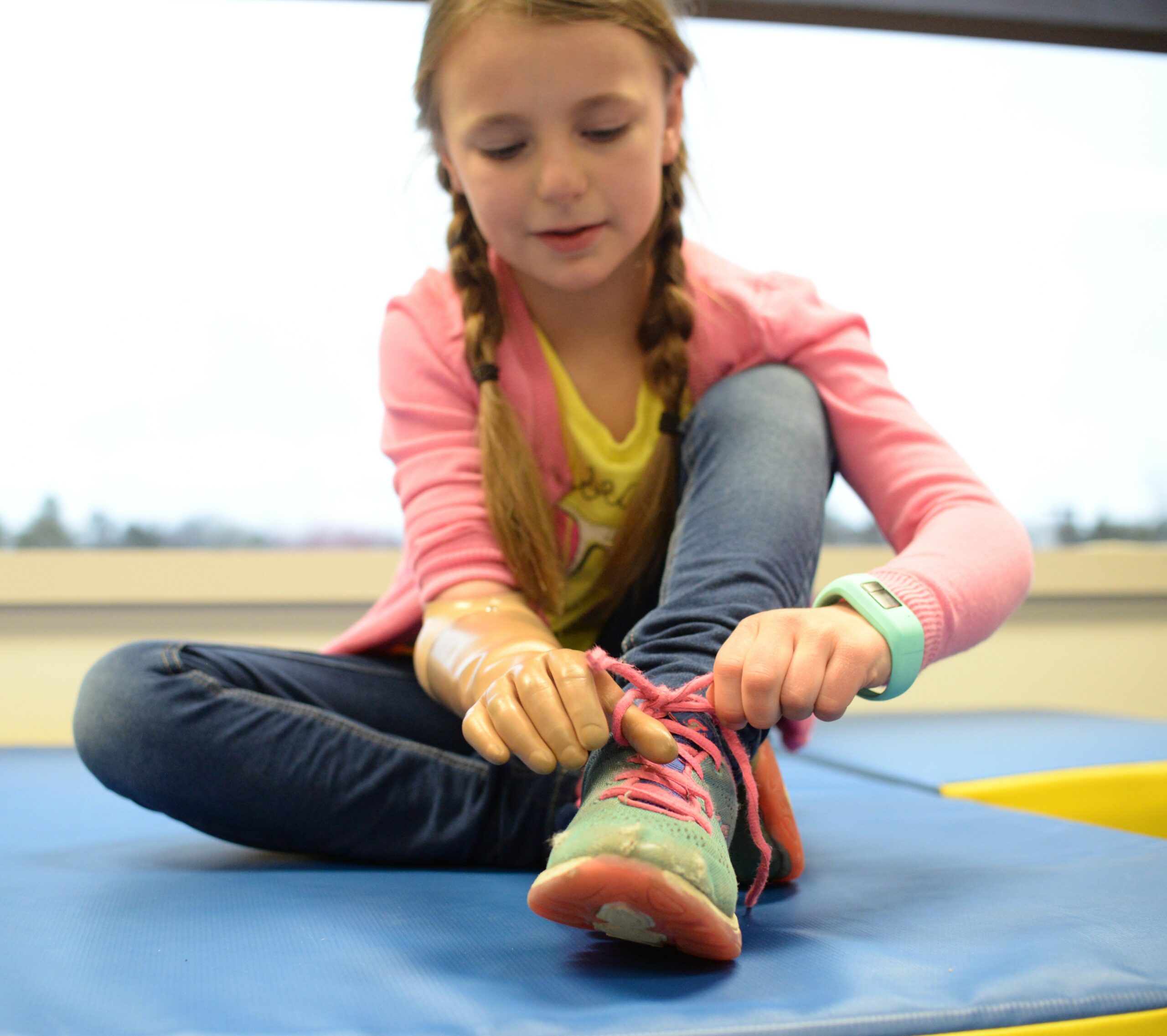 Girl with prosthetic hand tying her shoe